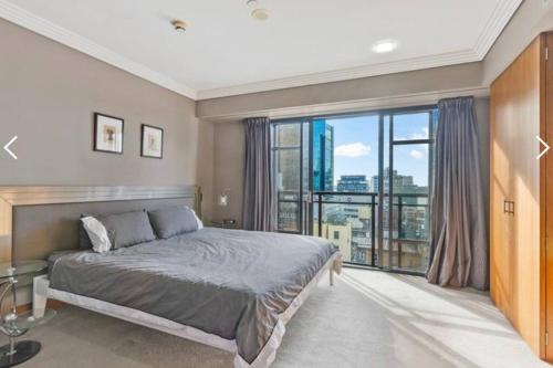 een slaapkamer met een bed en een groot raam bij Metropolis Dream in Auckland
