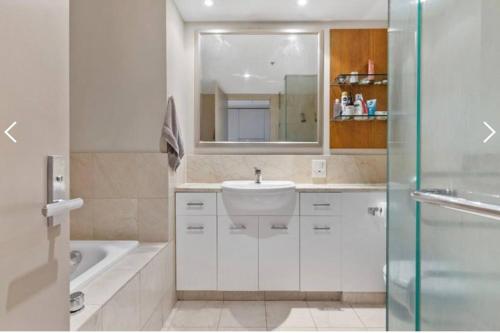 W łazience znajduje się umywalka, lustro i wanna. w obiekcie Metropolis Dream w Auckland