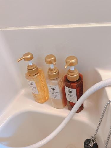 a bathroom sink with three bottles of soap at ひまわりHotel in Nagasaki