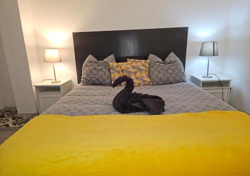 un canard noir assis sur un lit avec deux lampes dans l'établissement Castelnaudary - Appartement JARDIN, à Castelnaudary
