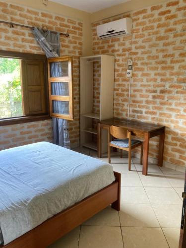 1 dormitorio con cama, escritorio y mesa en Point vert en Kribi