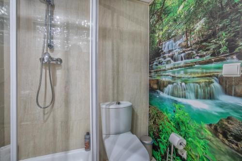 a bathroom with a shower and a toilet with a waterfall mural at Apartamento Esmeralda & Centro & Parking in Córdoba