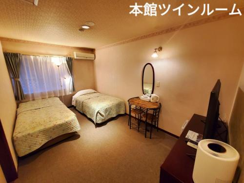日光市にある日光素泊まりの宿 憩～ikoi～のベッドが2つと鏡があるホテルの部屋
