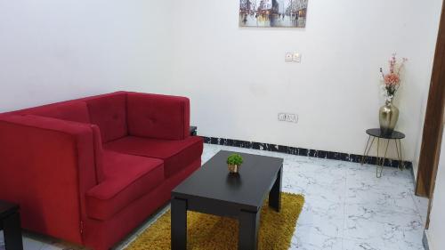 a living room with a red couch and a table at NESTAPARTMENTS , Orchid Road , VAN DANIEL'S STREET, LEKKI , Ensuite ,WiFi in Lagos