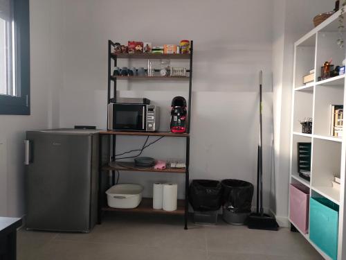 a kitchen with a refrigerator and a microwave on a shelf at relax al pie de la alfaguara in Alfacar