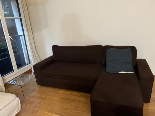 a brown couch with a blue pillow in a living room at Cosy studio Puteaux in Puteaux