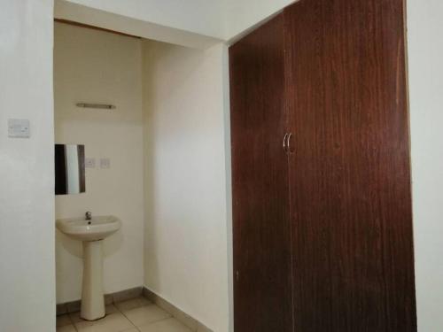 ein Badezimmer mit einer Holztür und einem Waschbecken in der Unterkunft Entire serviced 2-bedroom apartment in Thindigua in Nairobi