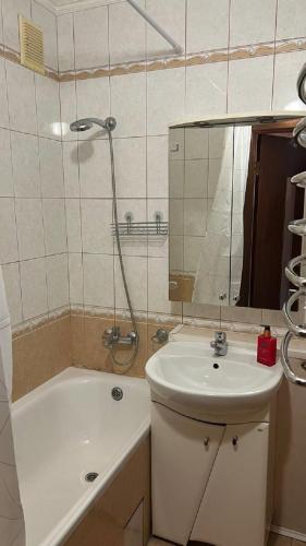 a bathroom with a sink and a tub and a mirror at Obolonskiy Prospekt Apartments 16Є in Kyiv