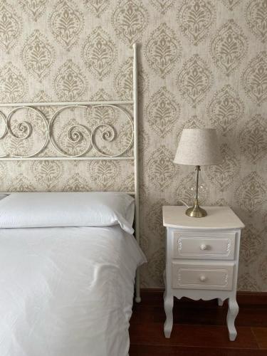 a bedroom with a bed and a nightstand with a lamp at Suite Comares in Granada