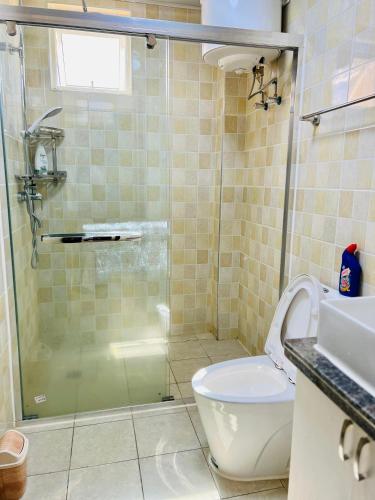 a bathroom with a glass shower and a toilet at Fully furnished 3 bedroom apartment in Mirembe Villas Kigo, Uganda in Kigo