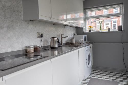 a kitchen with white cabinets and a washer and dryer at Homestay near Roundhay Park, North Leeds in Leeds
