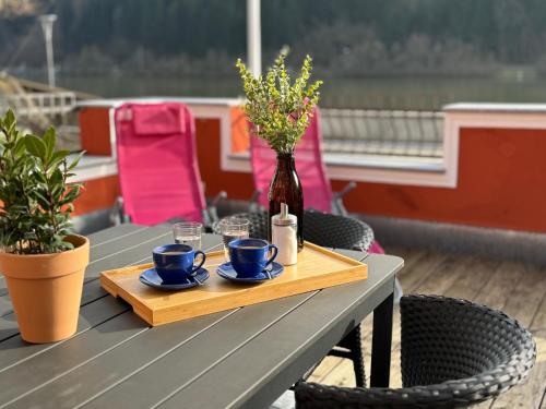 a table with two cups and a vase with flowers at Terrassenwohnung mit Donaublick in Obernzell