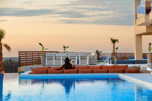 a person sitting on a couch next to a swimming pool at Vellis Residence in Stavromenos