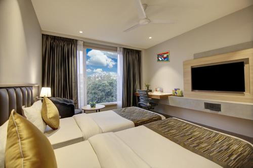 a hotel room with a couch and a flat screen tv at East Park Inn in New Delhi