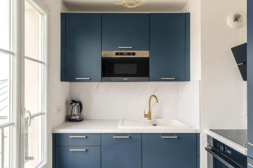 une cuisine avec des armoires bleues et un évier dans l'établissement Cosy Proche Disneyland Paris, à Serris