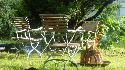 two chairs sitting next to a fire in the grass at Die Remise - Schmidsfelden 12 - 88299 Leutkirch im Allgäu in Leutkirch im Allgäu