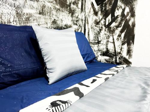 a bed with a blue sheet and a pillow with a skull andocrates at Kost Harian Semarang Murah in Semarang