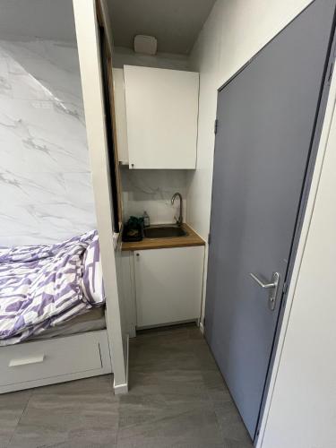 um pequeno quarto com uma cama, um lavatório e uma porta em Studio PetitCocon 2min métro 11 Carnot Romainville em Noisy-le-Sec