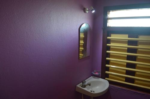 een paarse badkamer met een wastafel en een spiegel bij Hotel Mainak Mandarmani in Mandarmoni
