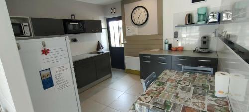 a kitchen with a table and a clock on the wall at Aux Passagers de la baie 2 in Le Crotoy