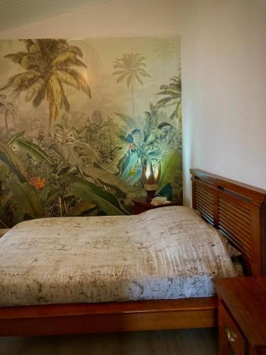1 dormitorio con un mural de palmeras en la pared en Les capucines du volcan Plaine des cafres, en Le Tampon