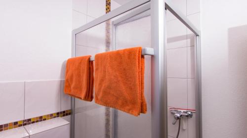 an orange towel is hanging in a shower at Weingut Roth in Kindel