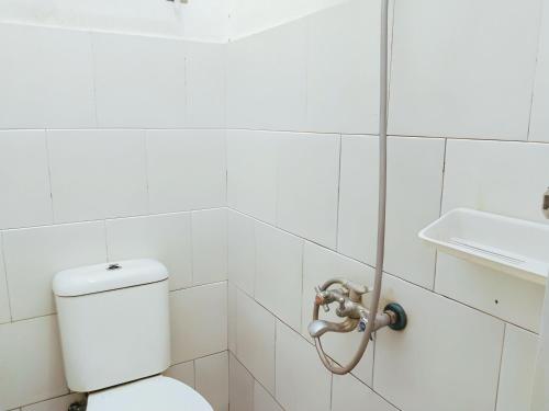 ein weißes Bad mit einem WC und einem Waschbecken in der Unterkunft Eleven Guest House Syariah in Sukaraja