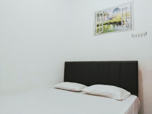 ein Bett mit einem schwarzen Kopfteil und zwei Kissen in der Unterkunft Eleven Guest House Syariah in Sukaraja