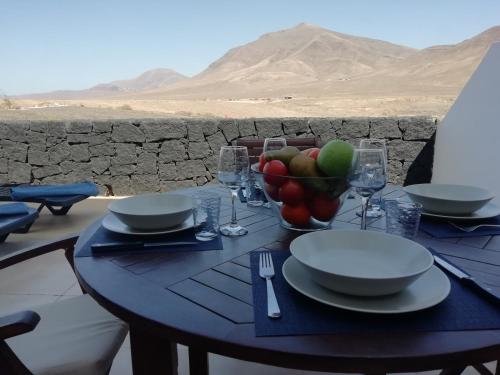 una mesa con un bol de frutas y platos en ella en Villa Pura Vida en Playa Blanca