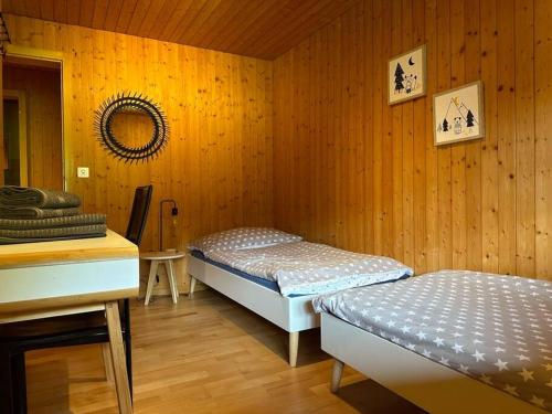 a bedroom with two beds in a wooden wall at Ferienwohnung im Chalet Bergruh - Hasliberg Reuti in Hasliberg