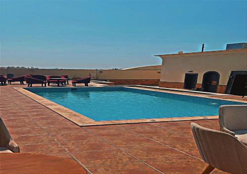 a swimming pool on a patio with chairs and tables at Sansa Hotel in Jeddah