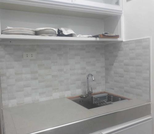 een keuken met een wastafel en een plank met borden bij 2Ms in Baguio