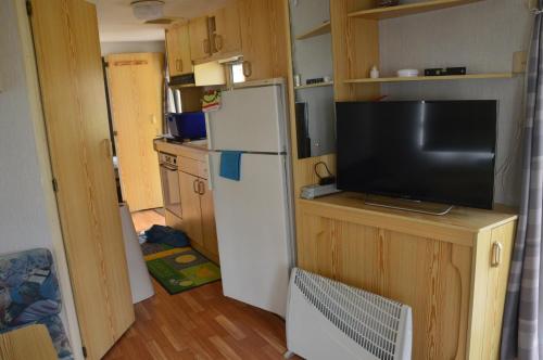 uma pequena cozinha com um frigorífico e uma televisão em Camping Chon du Tarn em Bédouès