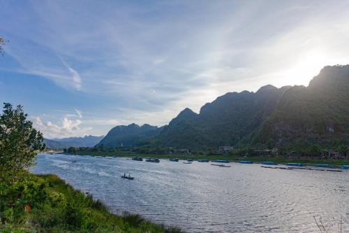 een rivier met boten erop met bergen op de achtergrond bij Applebee's Homestay in Phong Nha