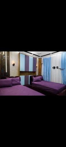 een slaapkamer met 2 bedden met paarse lakens en gordijnen bij شقه فندقيه للايجار بكمبوند كريستال بلازا in Caïro