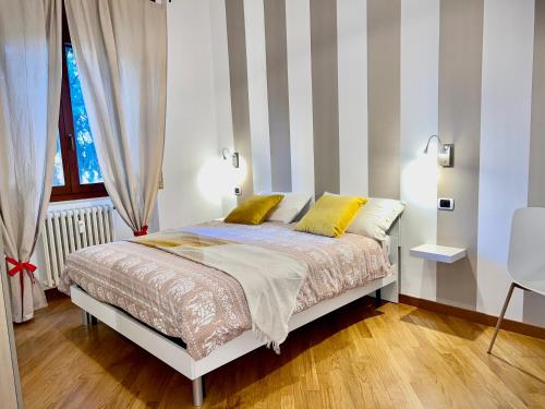 1 dormitorio con cama con almohadas amarillas y pared a rayas en Gallery Fiera Milano, en Cornaredo