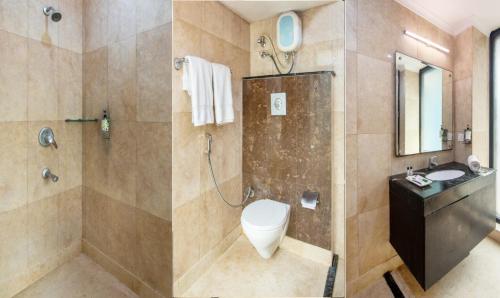 twee foto's van een badkamer met een toilet en een douche bij Cordial Home in New Delhi