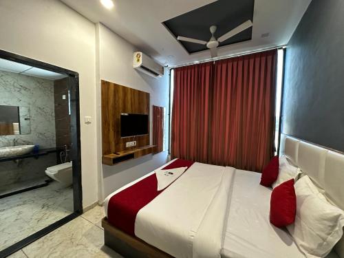 a bedroom with a bed and a bathroom with a television at Hotel Dumas Near Airport in Surat