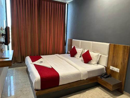 - une chambre dotée d'un grand lit avec des oreillers rouges et blancs dans l'établissement Hotel Dumas Near Airport, à Surate