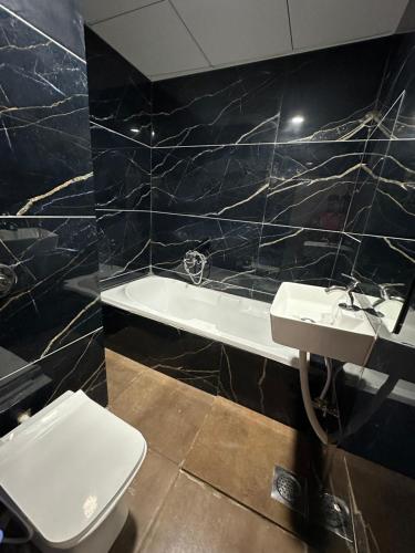 a bathroom with a toilet and a sink and a tub at Hotel Dumas Near Airport in Surat