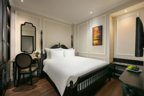 a bedroom with a large white bed and a desk at Amira Hotel Hanoi in Hanoi