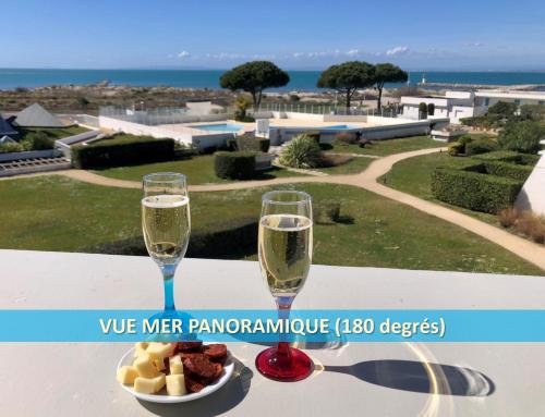 a table with two glasses of champagne and a bowl of food at CAMARG'Beach Vue mer-Piscines-Plages-Tennis-Parking-4PERS in Le Grau-du-Roi