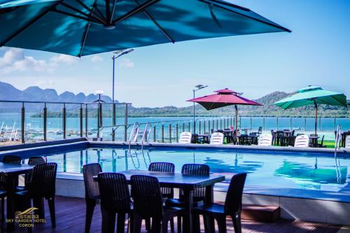 una piscina con mesas, sillas y sombrillas en Sky Garden Hotel, en Corón