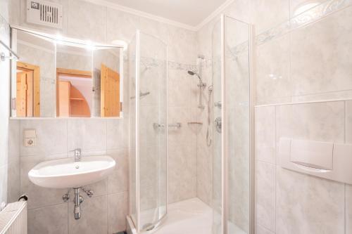 ein weißes Bad mit einem Waschbecken und einer Dusche in der Unterkunft Haus Holzer in Sankt Andrä im Lungau