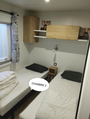 - 2 lits dans une chambre avec un panneau indiquant le changement dans l'établissement mobil-home k121 au camping les Charmettes, aux Mathes