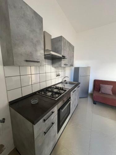 a kitchen with stainless steel appliances and a red couch at Aurora e Alba in Casalabate