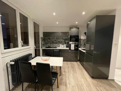 a kitchen with a white table and black appliances at Charmant appartement une chambre in Ville-la-Grand