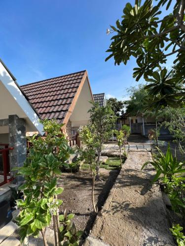 a garden with trees in front of a house at Meno Melani guesthouse in Gili Meno