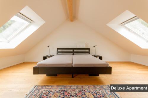 a attic bedroom with a bed and two windows at Rurtal de luxe in Simmerath