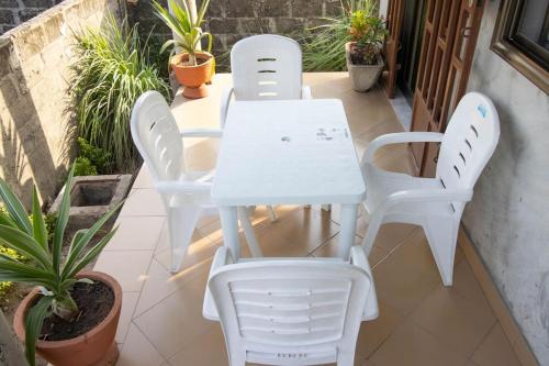 3 sillas blancas y una mesa en el patio en Super Appartement à 10mn de la mer, en Cotonou